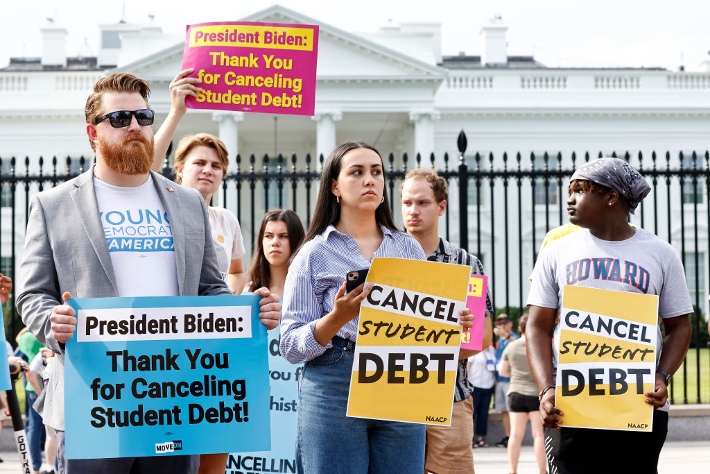 student loan borrowers holding signs thanking Biden for canceling student debt